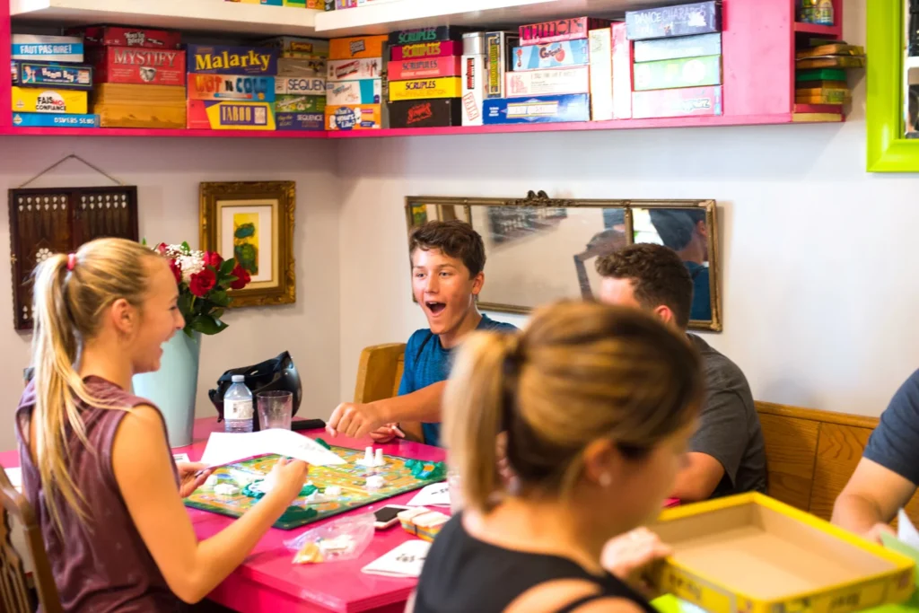 Guests laughing over a board game at Le Moque-Tortue